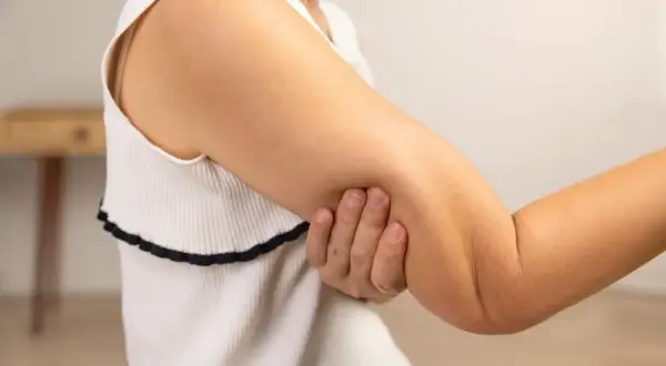En person håller om sin arm, där man kan se tydliga muskler i armen.