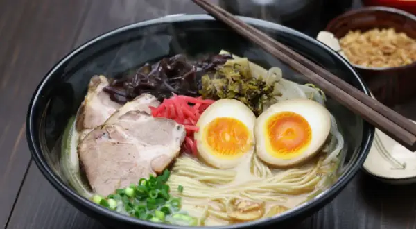 Parujący ramen z grubym makaronem, plastrami wieprzowiny, jajkiem na pół i szczypiorkiem. Idealny wybór, jaki makaron do ramen!