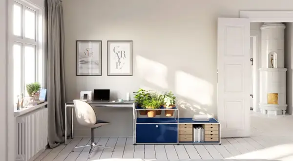 Accogliente stanza studio piccola con scrivania, piante e un'antica stufa in maiolica visibile attraverso una porta aperta.