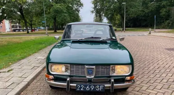 En grön Saab 99 står parkerad på en tegelstensbelagd uppfart, redo för en tur genom svenska landskap.