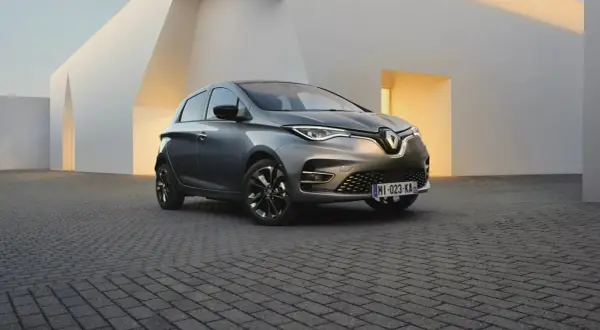 Une Renault Zoe grise, symbole de la mobilité électrique et de son autonomie, se gare devant une architecture moderne aux lignes épurées.