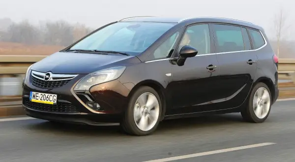Ciemnobrązowy Opel Zafira Tourer 1.4 Turbo na drodze. Kierowca za kierownicą.