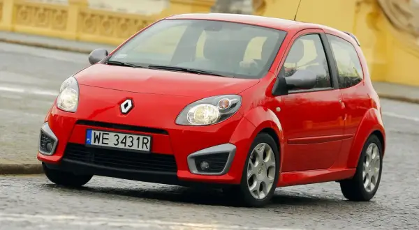 Czerwone Twingo RS na mokrej nawierzchni, z widocznym kierowcą za kierownicą.