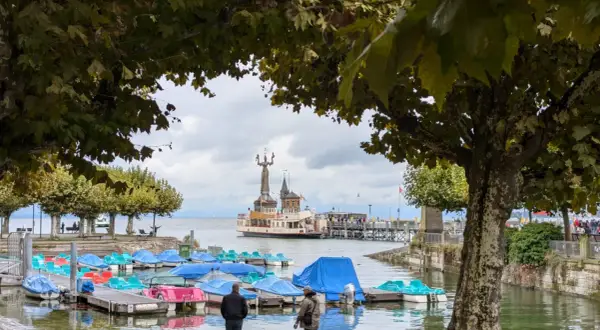Bunte Tretboote liegen am Steg, im Hintergrund die Imperia-Statue und ein Dampfer am St. Galler See.
