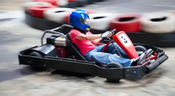 Dziecko w niebieskim kasku śmiga gokartem po torze w Warszawie. Emocjonująca jazda gokartami dla dzieci.