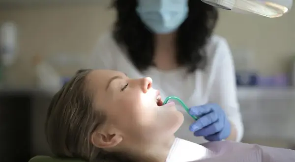 Pacjentka u dentysty, która ma otwarte usta i zielony przyrząd w jamie ustnej.