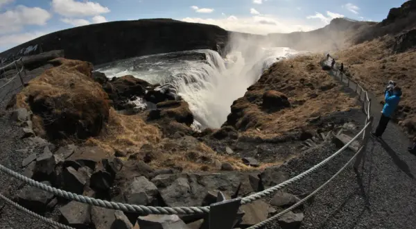 Wodospad Gullfoss na Islandii. Tłumy turystów podziwiają potęgę natury, tworząc malowniczy ruch drogowy na ścieżkach.