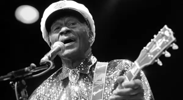 Chuck Berry, ein verstorbener Rockmusiker, singt ins Mikrofon und spielt Gitarre.