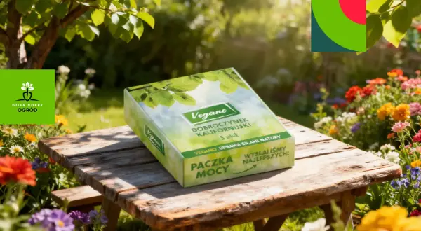 Pudełko z napisem "Vegano Dobroczynek Kalifornijski" na drewnianym stole w ogrodzie pełnym kwiatów.