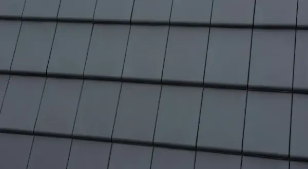 Zbliżenie na ciemnoszare dachówki ułożone w rzędy.