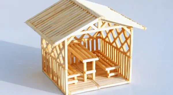 Miniaturowy domek z zapałek z ławkami i stołem. Inspiracja, jak zrobić domek z zapałek.
