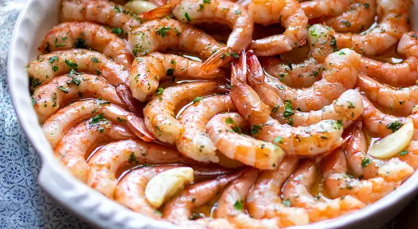 Gamberoni al forno succulenti, conditi con aglio e prezzemolo, pronti per essere gustati.