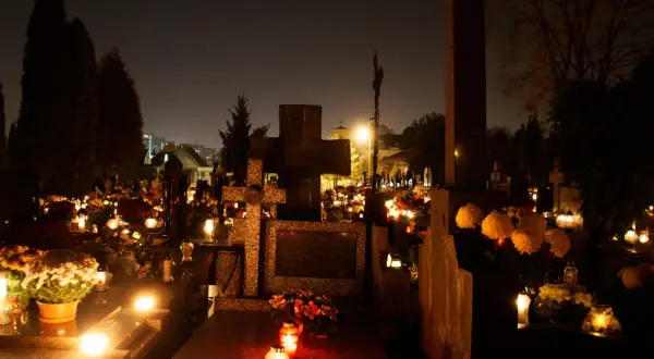 Nocny cmentarz 2 listopada, dzień zaduszny. Płonące znicze i kwiaty na grobach tworzą magiczny, choć melancholijny nastrój.