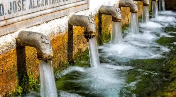 Fuente alta agua brota de varios grifos de metal, creando un riachuelo burbujeante.