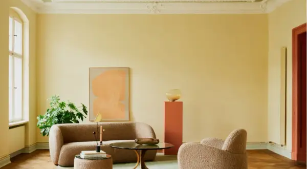 Sanfte gelbe Wände mit einer dezenten Streichtechnik Wand, kombiniert mit einem grünen Deckenanstrich, schaffen eine warme Atmosphäre. Ein beiger Bouclé-Sofa und Sessel laden zum Entspannen ein.