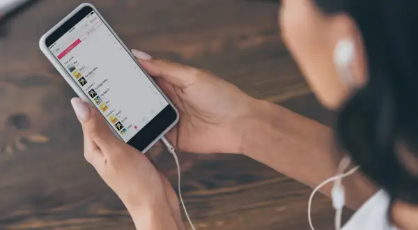 Kobieta wybiera muzykę na telefonie, by dowiedzieć się, jak dodać muzykę do relacji na Instagramie.