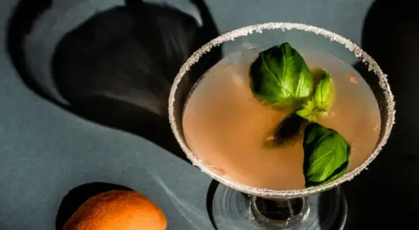 En läcker alkoholfri drink med basilika och en apelsinskal som dekoration.