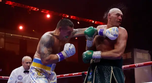 Boxer lands a punch as the referee watches. This intense moment captures the action, and in boxing, "UD" means a unanimous decision win.