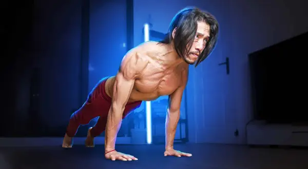 Un homme musclé en position de pompe, pratiquant la musculation poids du corps dans une pièce sombre éclairée par des lumières bleues.