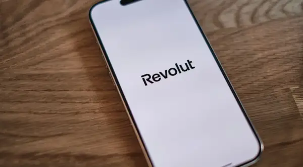 Telefon z logo Revolut na ekranie. Dowiedz się, jak wplacić pieniadze na Revolut, aby łatwo zarządzać finansami.