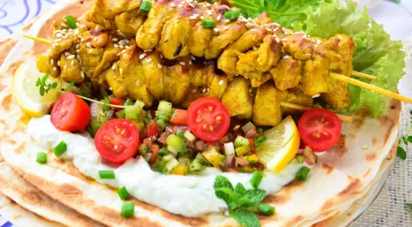 Pyszna shoarma z kurczaka na chlebku pita, z jogurtowym sosem, świeżymi warzywami i cytryną.
