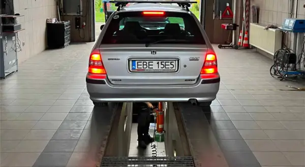 Srebrny Honda Civic na podnośniku w warsztacie. Tablica rejestracyjna EBE 15E5. Może poprzedni właściciel nie przerejestrował auta?