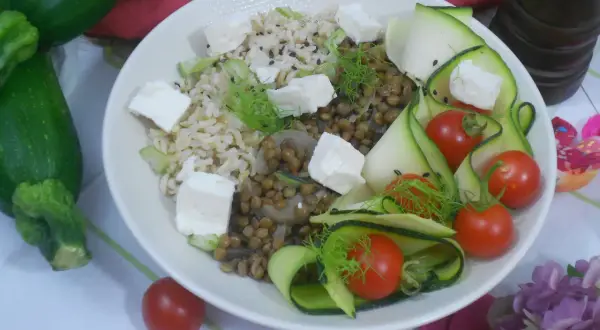 Salade de lentilles, riz, courgettes en rubans, tomates cerises et cubes de feta. Une assiette colorée et saine.
