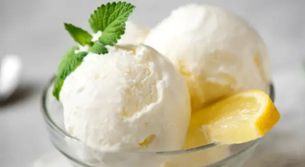 Delicioso helado casero de limón, servido en copa con menta y rodaja de limón. ¡Perfecto para aprender como hacer helado casero!