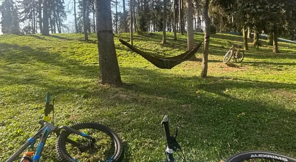 Relaks po rowerowej wycieczce po Warszawie. Hamak między drzewami, rowery czekają na dalszą trasę.
