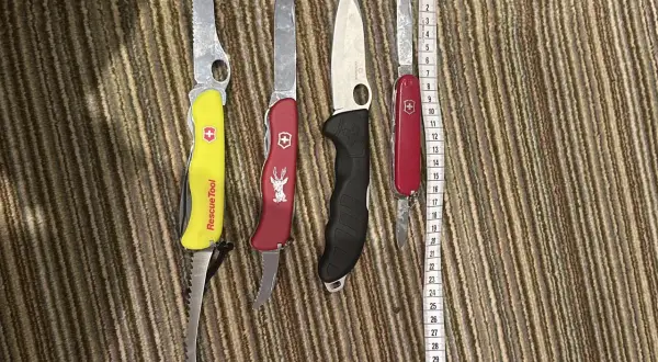 Cztery scyzoryki, w tym jeden z napisem "Rescue Tool", leżą obok miarki. Czy można przewozić nóż w bagażu rejestrowanym?