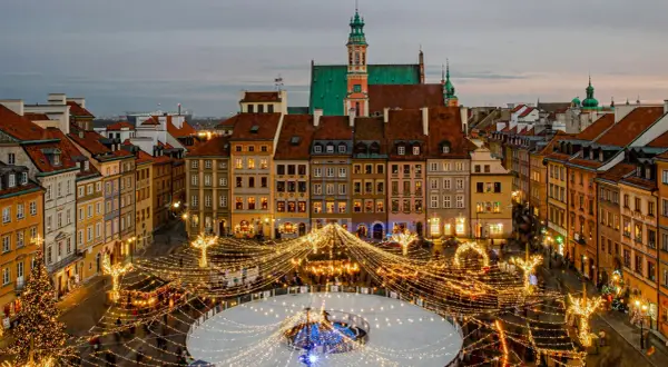 Magiczny zimowy wieczór w Warszawie. Rynek Starego Miasta rozświetlony tysiącami lampek, lodowisko i choinka tworzą idealny klimat na city break w Polsce.