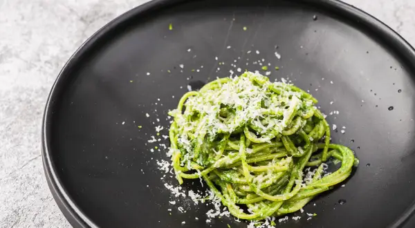 Ein Teller mit leckeren Nudeln mit Pesto, bestreut mit frisch geriebenem Parmesan.