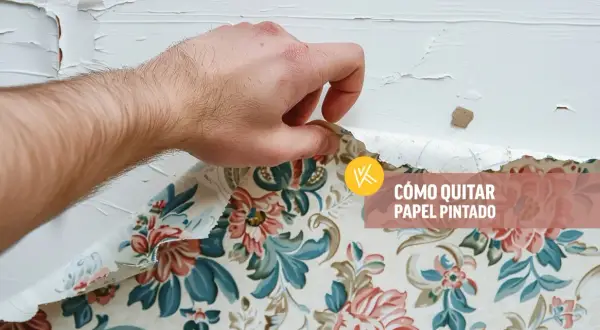 Mano retirando papel pintado floral de una pared blanca.