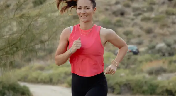 Femme souriante courant en extérieur, prouvant qu'il est possible de progresser en course à pied après 40 ans.