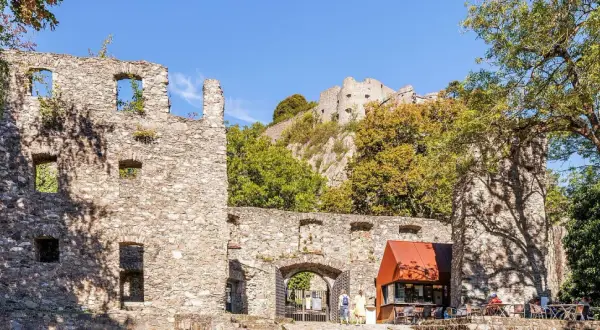 Ruinen der Hohentwiel Burg thronen auf einem Hügel. Im Vordergrund ein Torbogen und ein kleiner Kiosk.