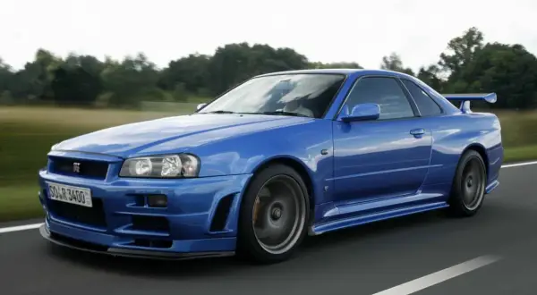 Niebieski Nissan Skyline GT-R R34 w ruchu. Marzenie wielu fanów motoryzacji, a jego cena wciąż rośnie.