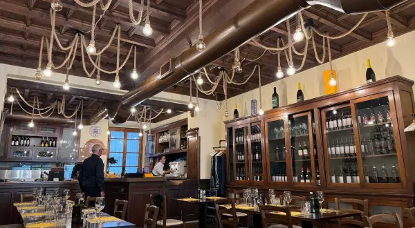 Interno di un ristorante con tavoli apparecchiati e una grande vetrina di vini. Un locale che potrebbe essere tra i migliori ristoranti di Milano per l'atmosfera.