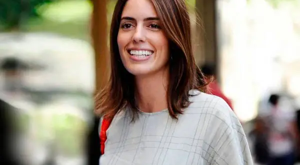 Sofía Palazuelo sonríe con su cabello castaño suelto y un vestido a cuadros.