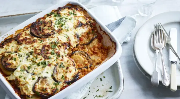 Un plat de moussaka végétarienne gratinée, garni d'aubergines et de persil frais, prêt à être dégusté.
