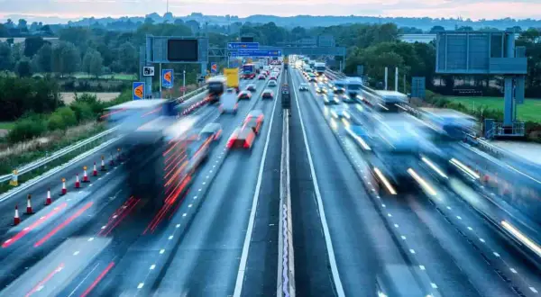 Autostrada w Wielkiej Brytanii, ruchliwy dzień. Wiele samochodów i ciężarówek w ruchu, tworząc smugi światła.