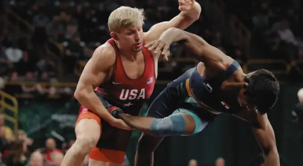 Två brottare i intensiv kamp. En bär USA:s färger, den andra en mörkblå dräkt. Spänningen är påtaglig i denna wrestling sverige-match.