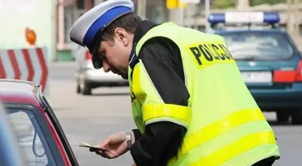 Policjant wręcza mandat. Zastanawiasz się, co jeśli nie zapłacę mandatu w ciągu 7 dni? Lepiej tego nie sprawdzać.