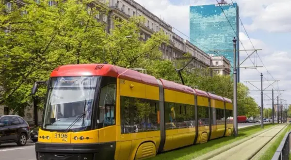 Żółto-czerwony tramwaj na zielonym torowisku. Zastanawiasz się, ile zarabia kierowca tramwaju?