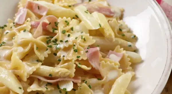 Leckere Spargel Pasta mit Schinken in cremiger Sauce, garniert mit Schnittlauch.