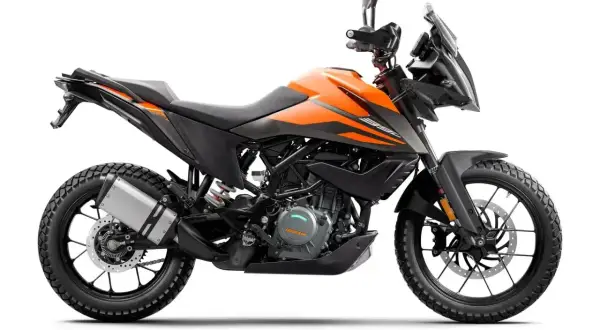 Pomarańczowy motocykl KTM 390 Adventure gotowy na przygodę, z agresywnym designem i terenowymi oponami.