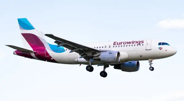 Samolot Eurowings z wysuniętym podwoziem na tle nieba.