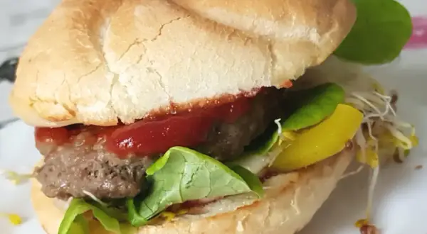 Pyszny burger z soczystym kotletem, sałatą, keczupem i żółtym serem. Idealny przykład, jak usmażyć burgera na patelni.