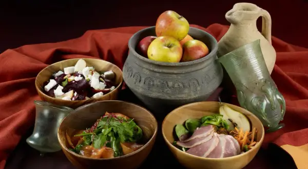 Essen wie im Mittelalter: Schalen mit Rote-Bete-Salat, Fleisch und Obst, dazu ein antiker Krug und Glas.