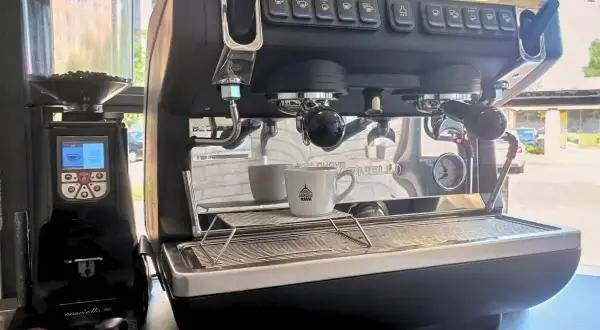 Macchina da caffè professionale con macinacaffè. Pronta per il consumo di caffè, con tazzina in attesa.