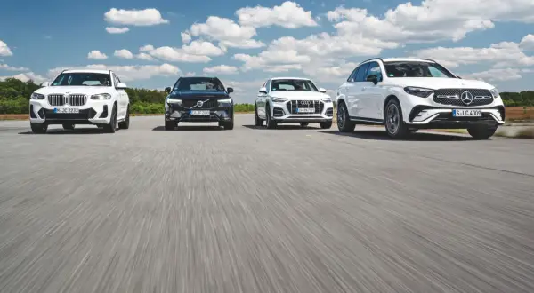 Białe i czarne SUV-y, w tym modele Mercedes, jadące po drodze.